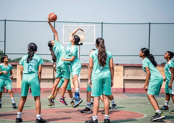 Students in a jump ball during a basketball match