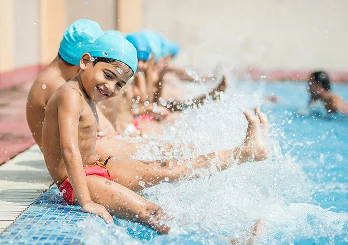 Young students splashing at the edge of the school pool